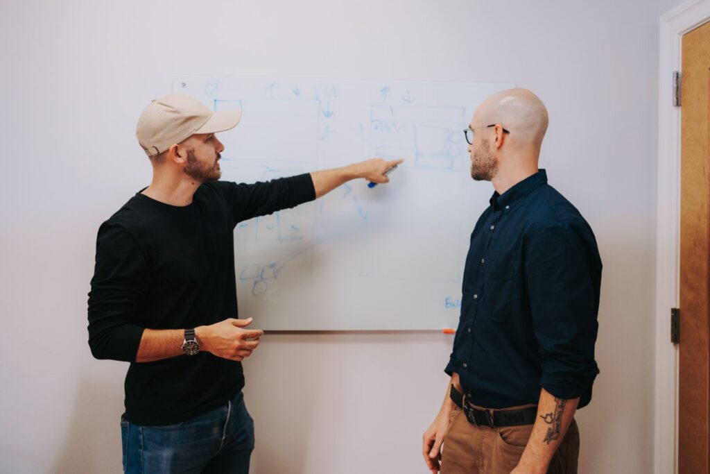 Two of the team walking through wireframes on a whiteboard